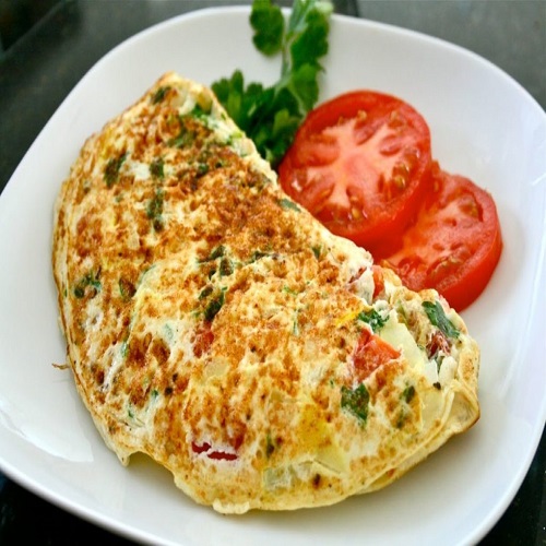 Imagem de um omelete com duas rodelas de tomates cortadas ao lado.